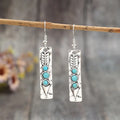 Silver geometric long strip earrings with inlaid turquoise details on a white background.