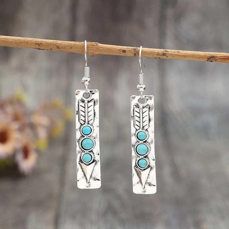 Silver geometric long strip earrings with inlaid turquoise details on a white background.