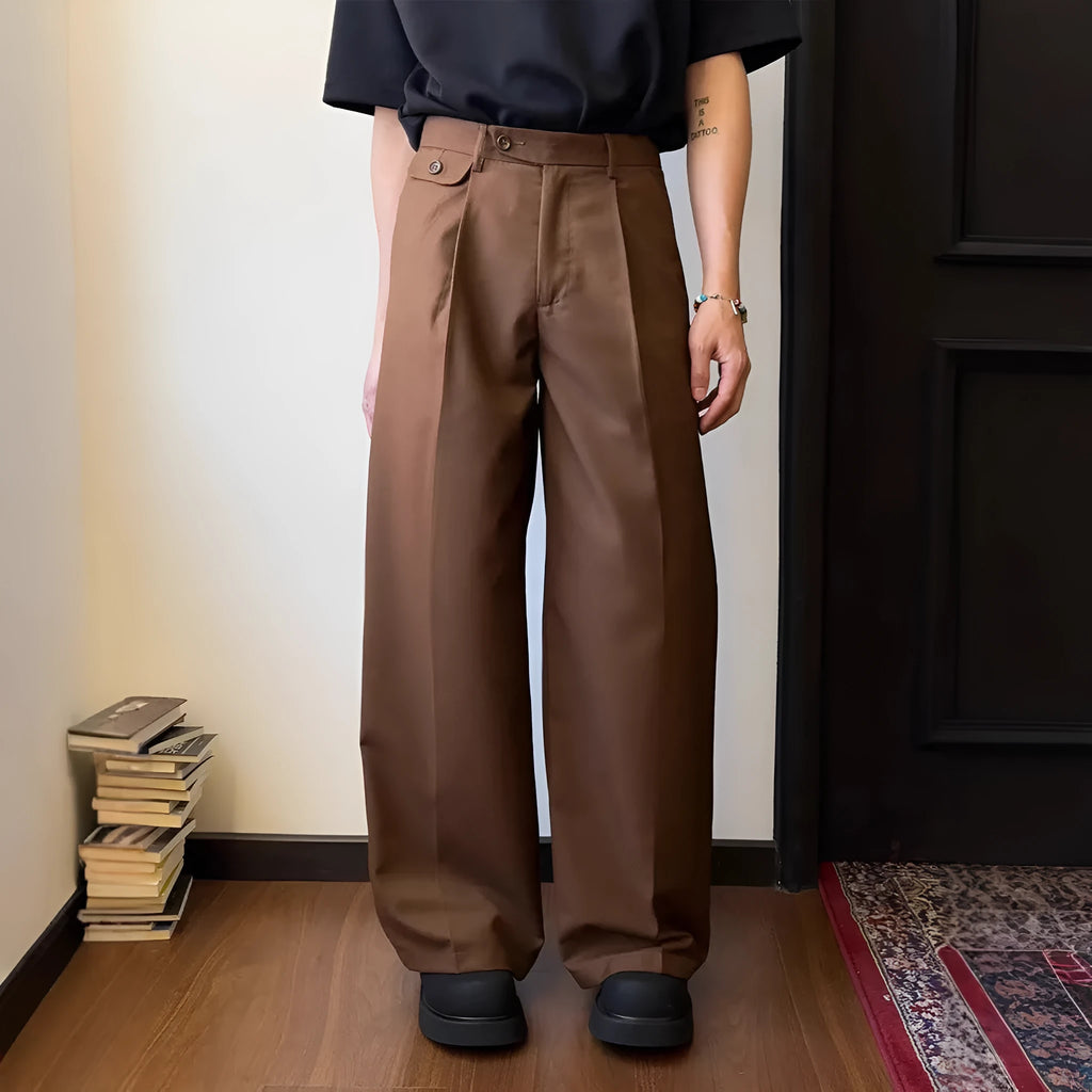 Men's brown straight-leg wide-drape trousers on a hanger, showing loose fit.