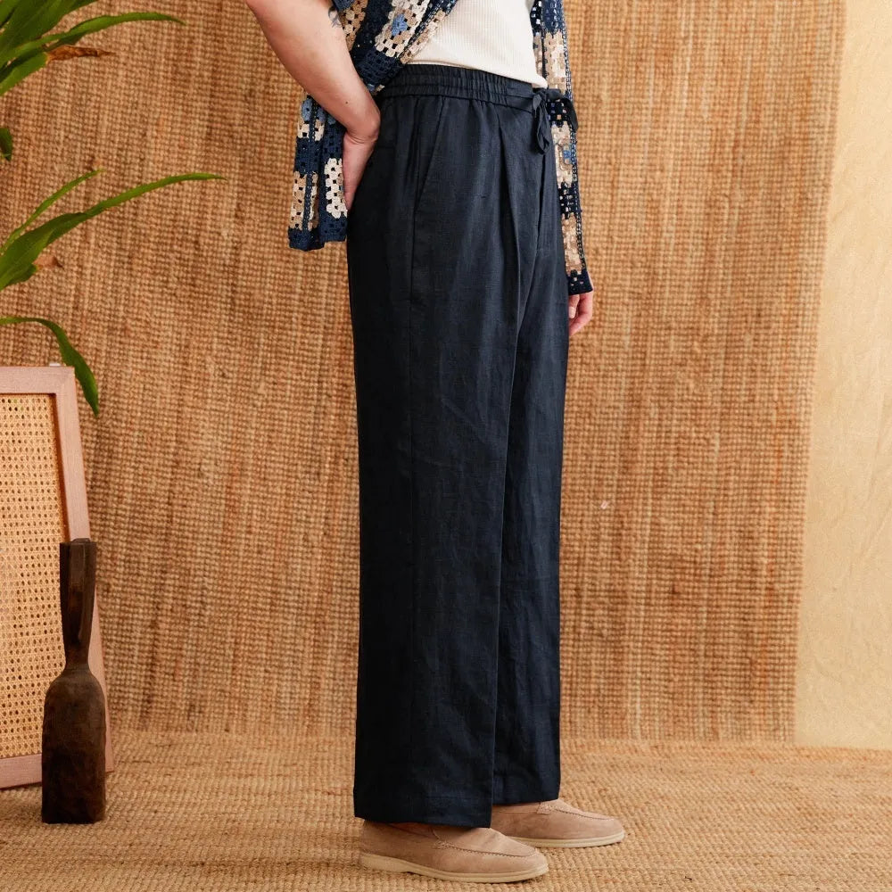 Navy blue linen high-waisted trousers with an elasticated waistband and straight-leg fit on a model.