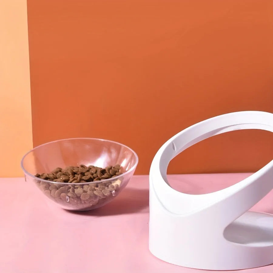 Clear plastic elevated cat food bowl with tilt design on white surface