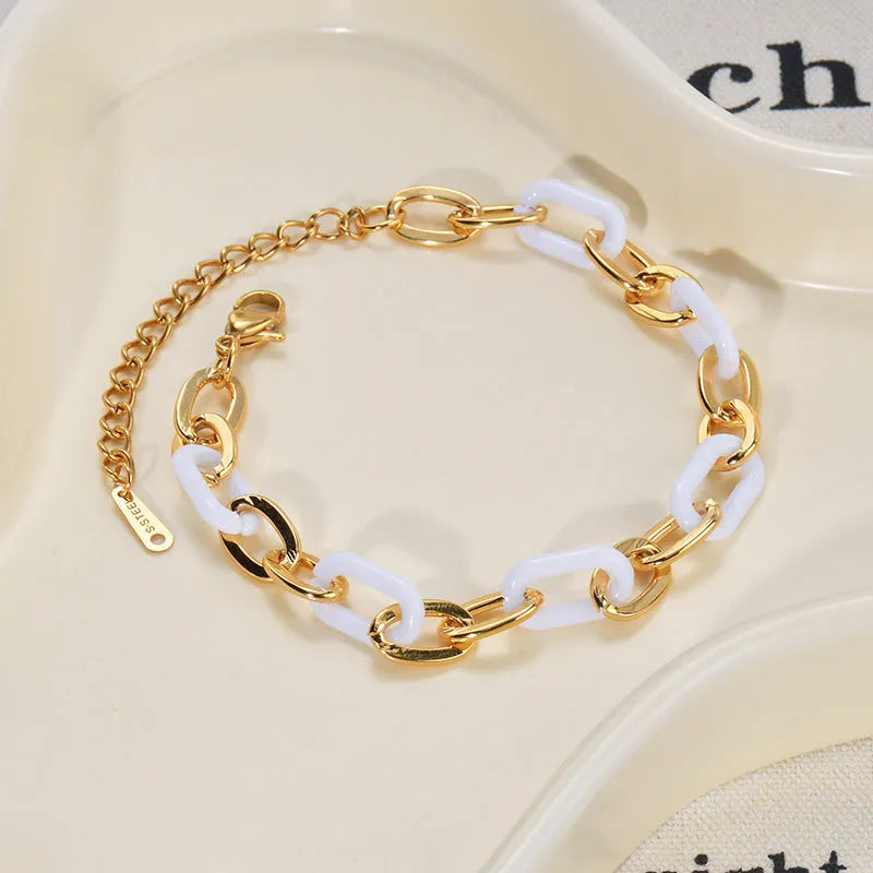 Close-up of a women's stainless steel bracelet featuring a double-layer heart charm with resin details.