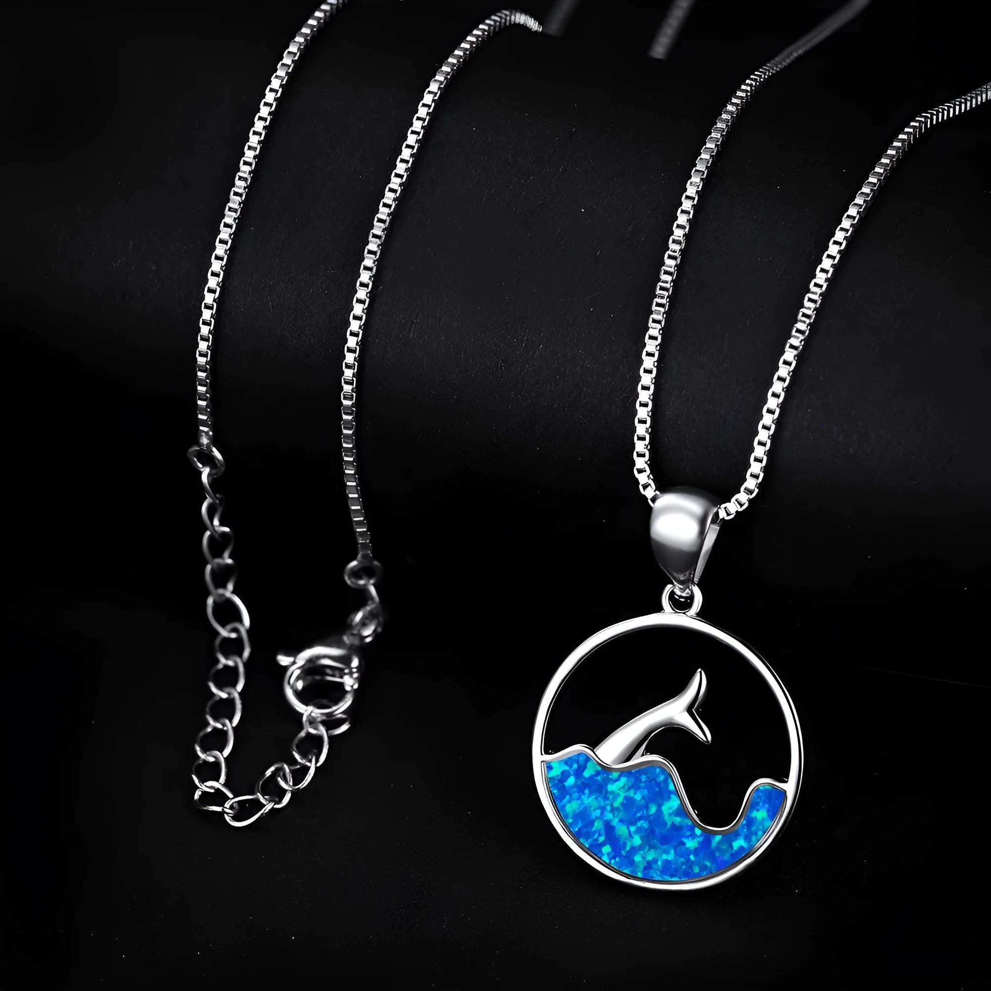 A round geometric fishtail pendant necklace with a white gold electroplated finish, shown in blue opal and white opal colour options.
