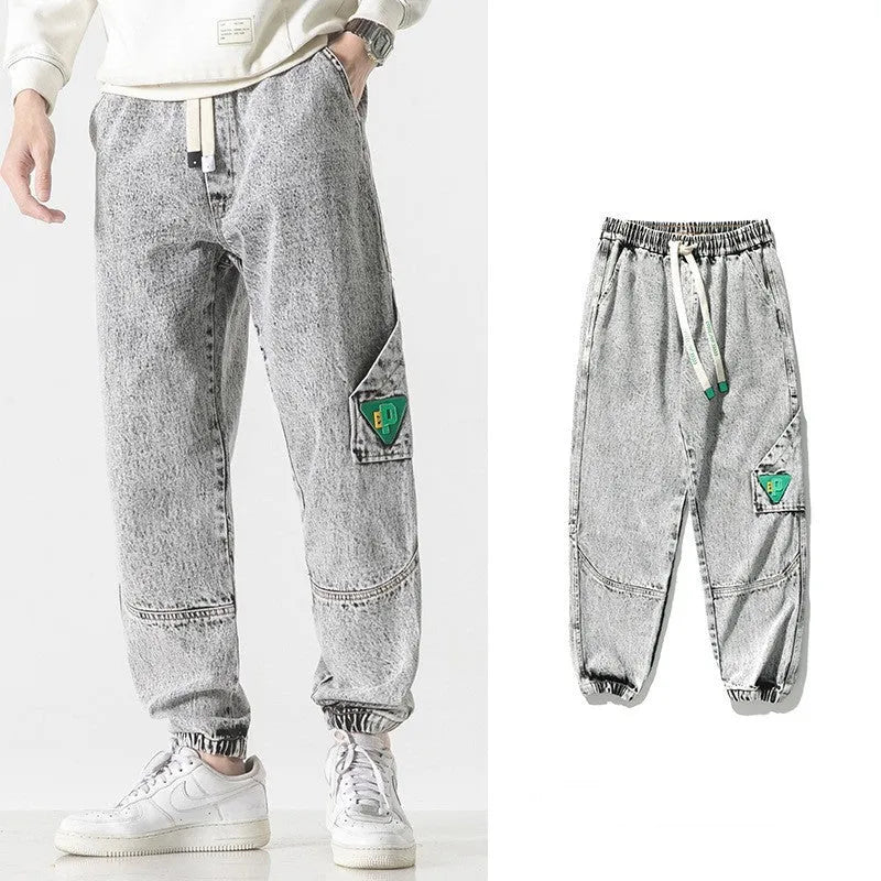 Men's loose-fit tapered cotton trousers in grey on a hanger.
