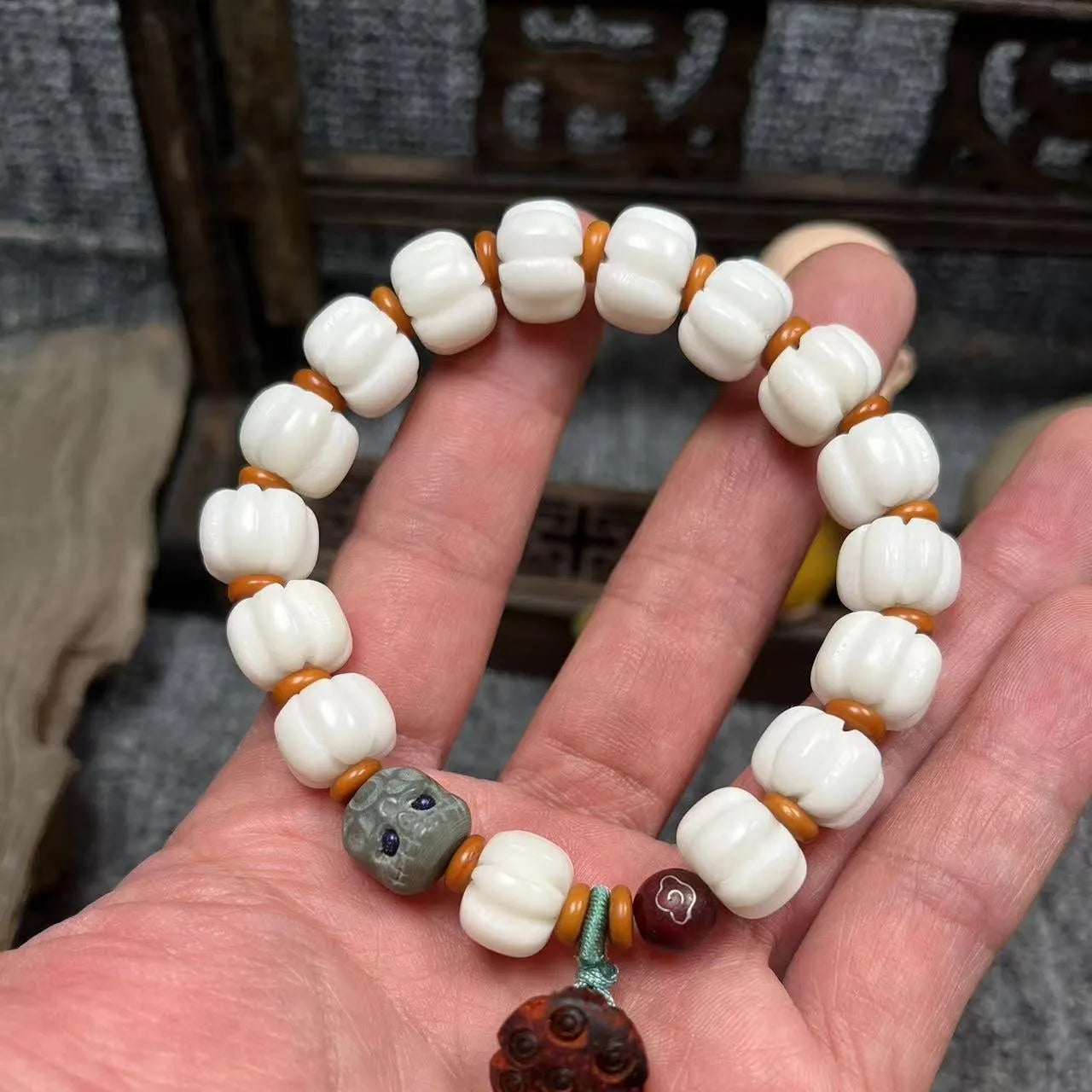 Carved Bodhi root bracelet with white jade, lotus, and pumpkin beads in various sizes.