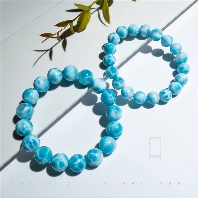 Blue handmade bodhi bracelet with natural sea-pattern crystal beads and pearl details on a wrist.