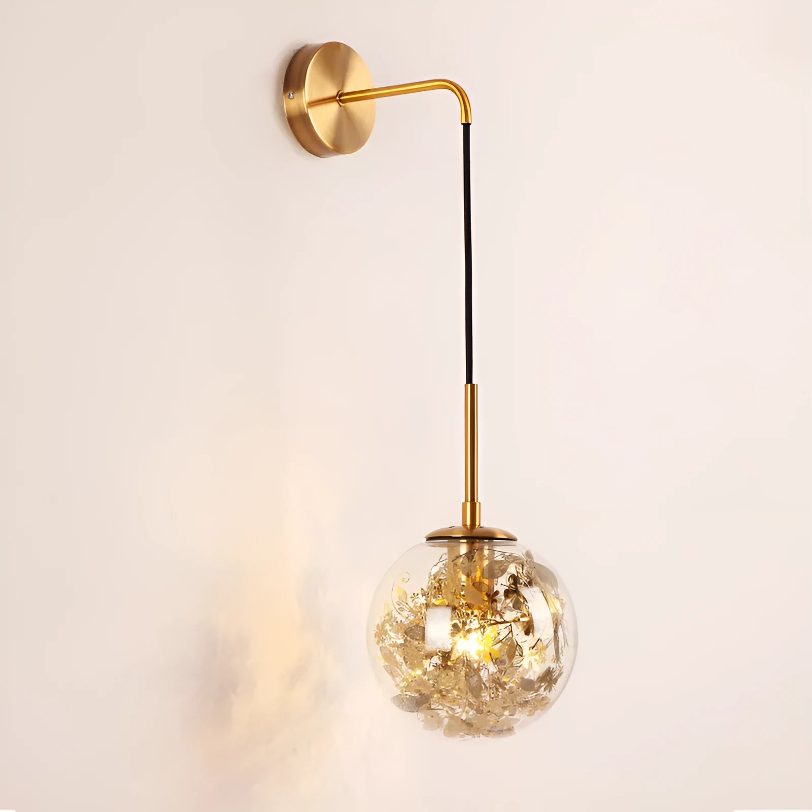 Simple modern glass wall lamp in golden flower finish mounted beside a bed.