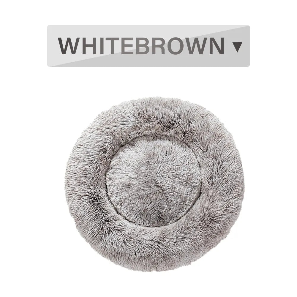 Fluffy donut-shaped dog bed in long plush material, shown in a light grey colour.