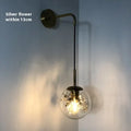 Simple modern glass wall lamp in golden flower finish mounted beside a bed.