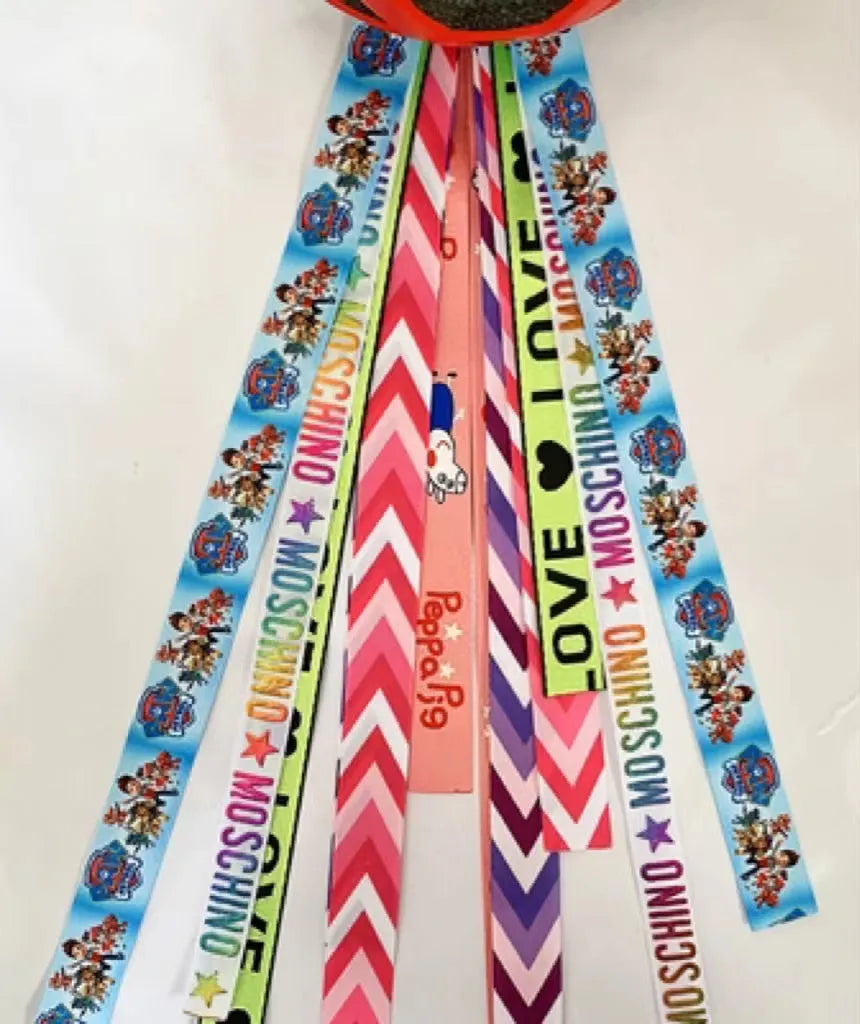 Colourful fabric helmet streamers for children's roller skating and ski helmets, shown in apricot, red, and grey.