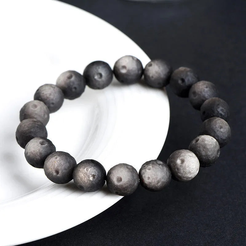 Obsidian crater ball bracelet with textured meteorite-like beads on elasticated cord