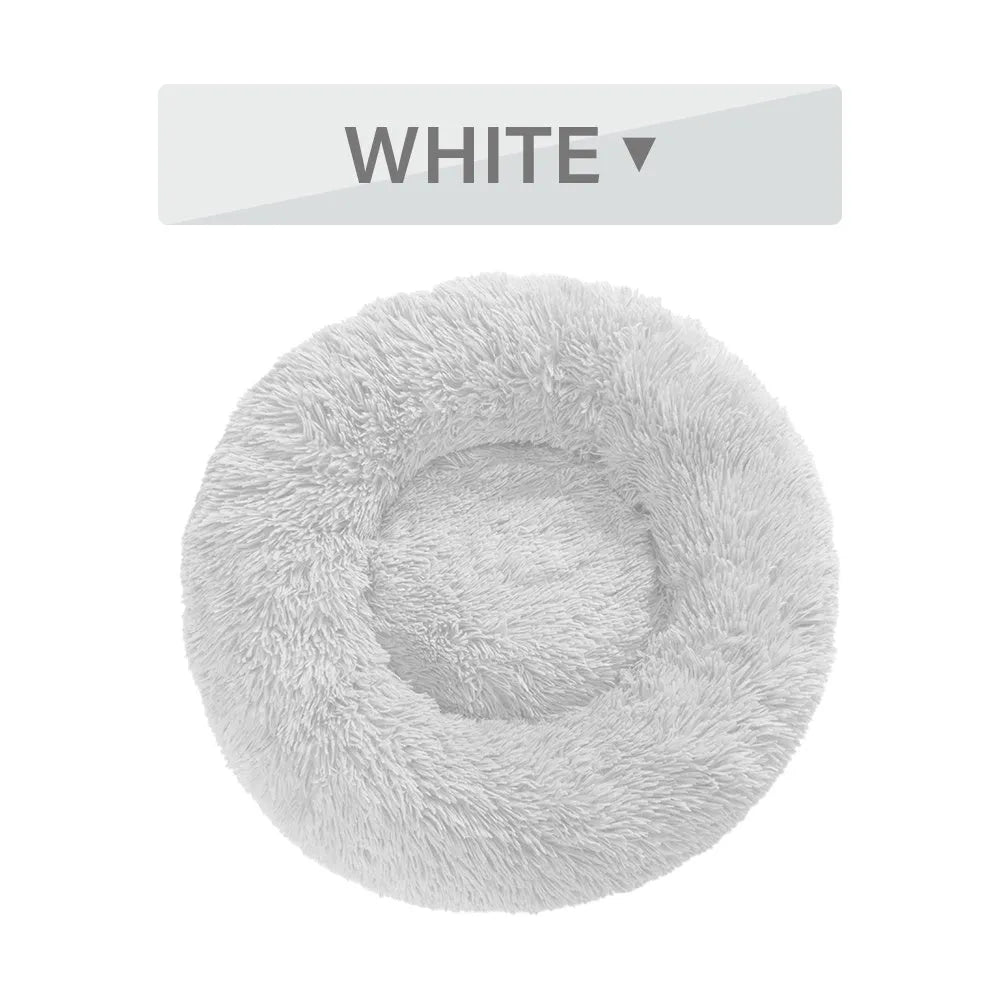 Fluffy donut-shaped dog bed in long plush material, shown in a light grey colour.