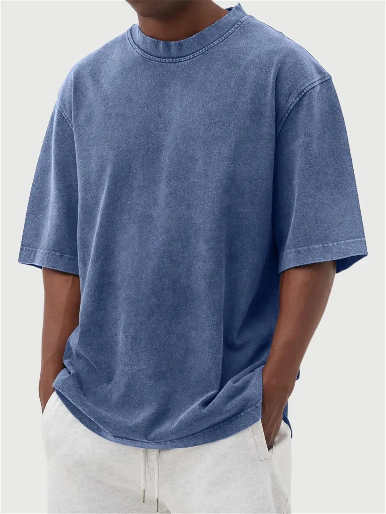 Man wearing a loose-fit, stone-washed polyester T-shirt in a solid colour with a distressed finish.