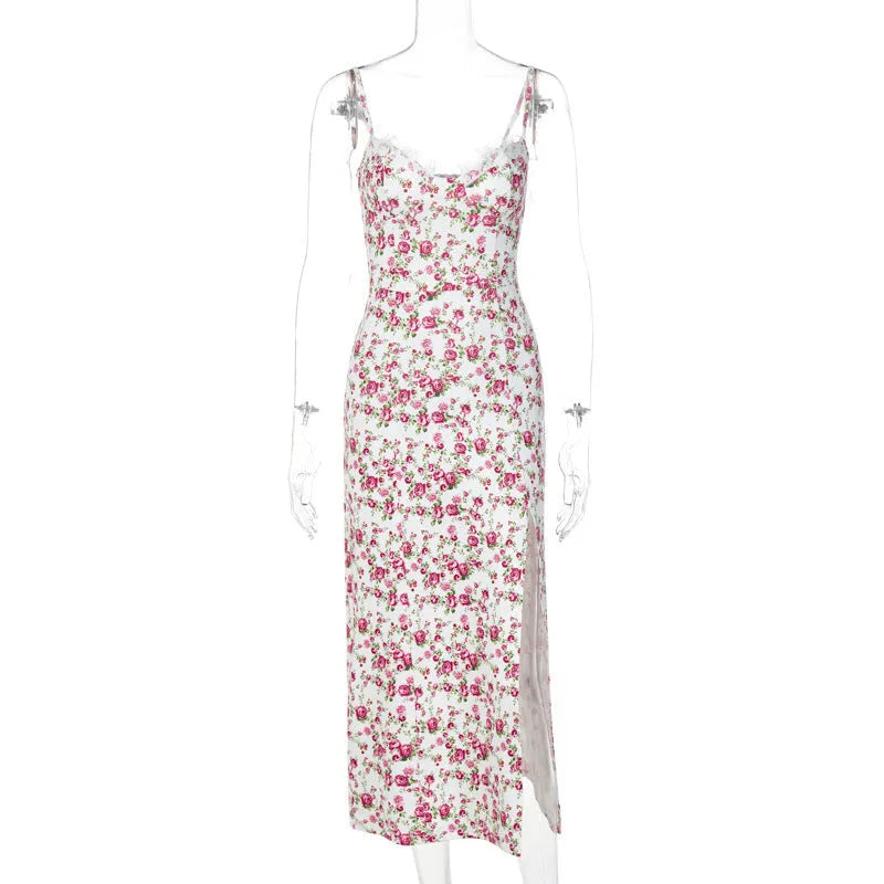 A woman wearing a long blue dress with a lace floral print, a side slit and thin suspender straps.