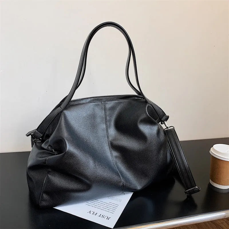 Large horizontal soft PU messenger bag in black with zip opening and long shoulder strap.