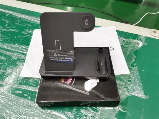 Black folding 4-in-1 wireless charger showing vertical stand mode charging an iPhone, with an Apple Pencil on its charging spot.