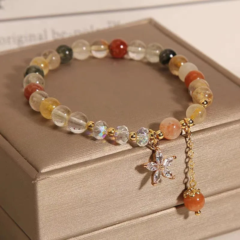Colourful hair crystal bracelet with cat's paw, flower, butterfly, and coin purse charms on an adjustable band.