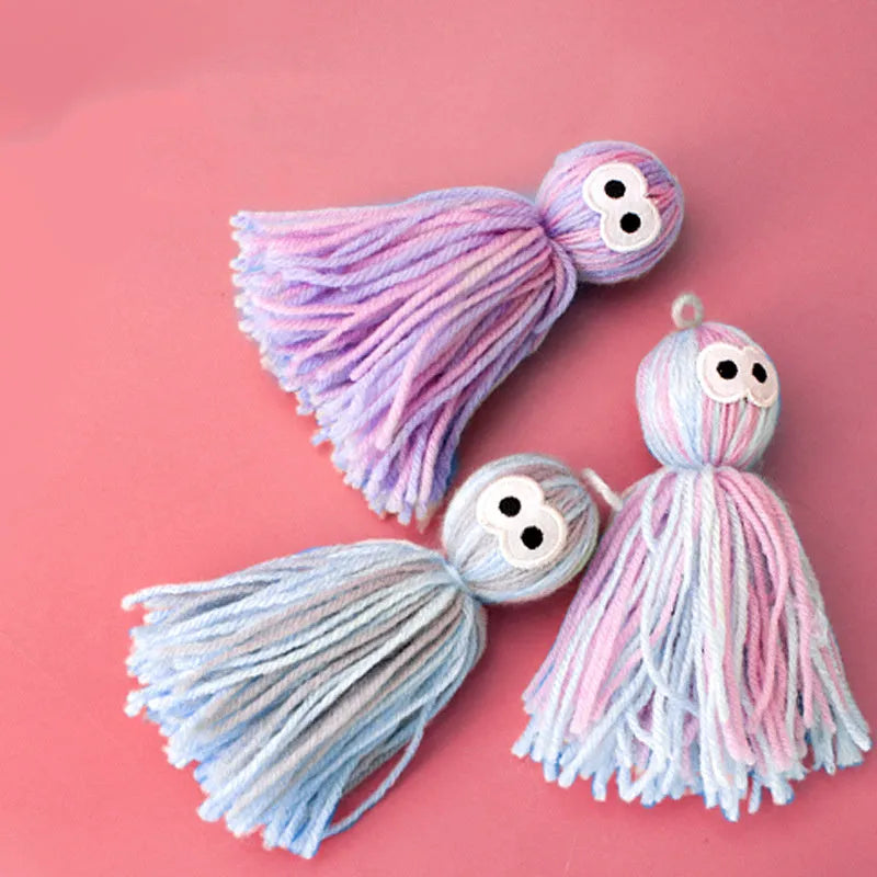 Blue grey wool ball cat toy with teaser stick, shown hanging and on a surface.