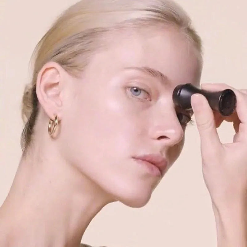 Portable black volcanic stone roller for oily skin control on a pink background.