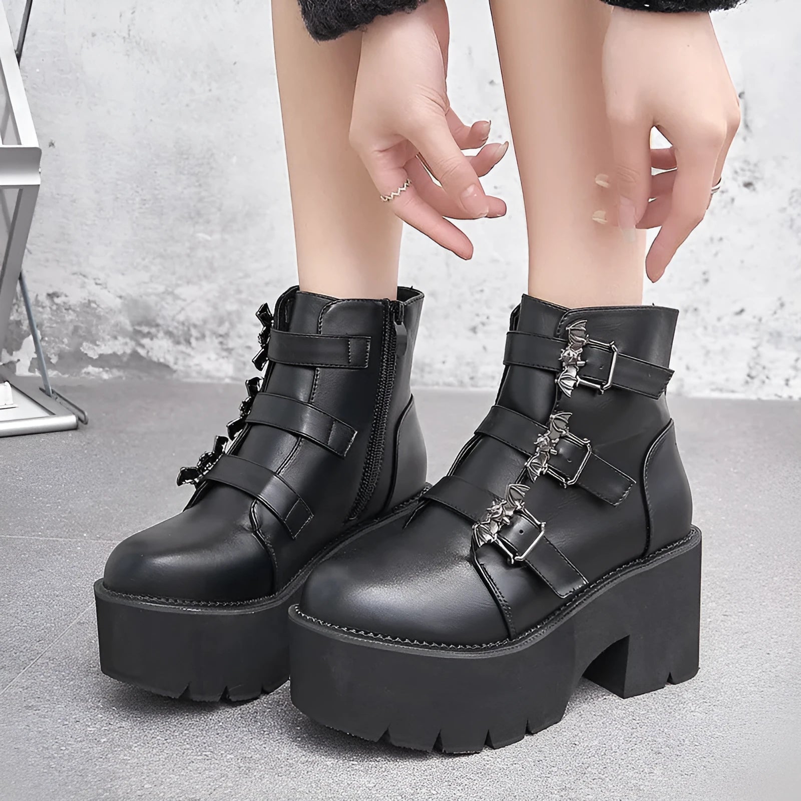 Black women's punk-style Martin ankle boots with a bat-shaped buckle and side zipper.