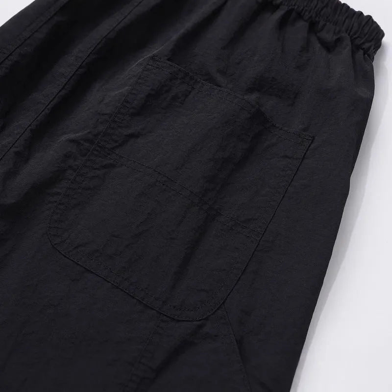Black baggy men's paratrooper pants with a drawstring waist and three-dimensional cutting.