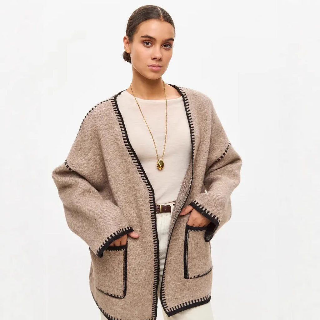A loose, mid-length knitted cardigan with a front lace-up detail, shown in a camel colour.