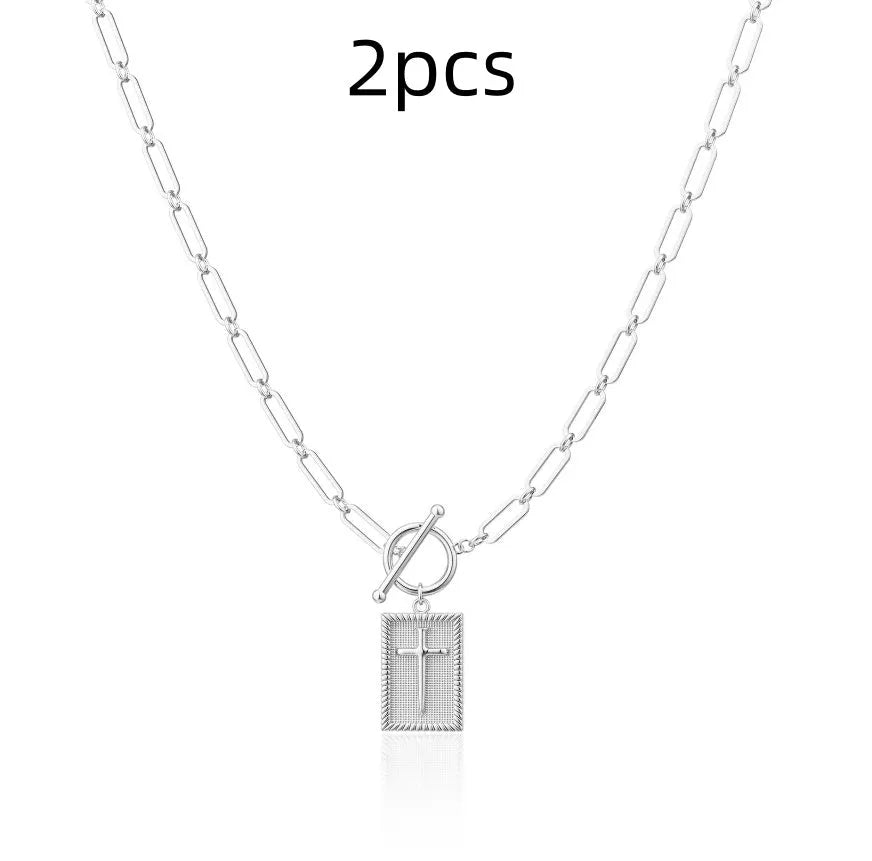 Gold electroplated stainless steel clip chain necklace with cross and square geometric pendant on white background