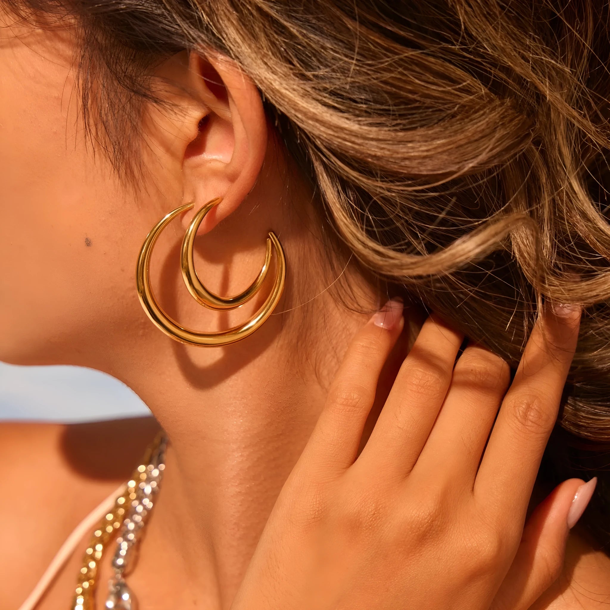 A pair of simple round titanium stainless steel hoop earrings shown in both gold and steel finishes.