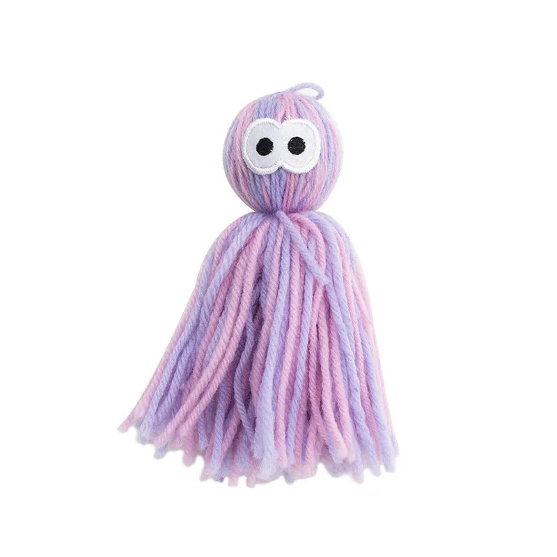 Blue grey wool ball cat toy with teaser stick, shown hanging and on a surface.