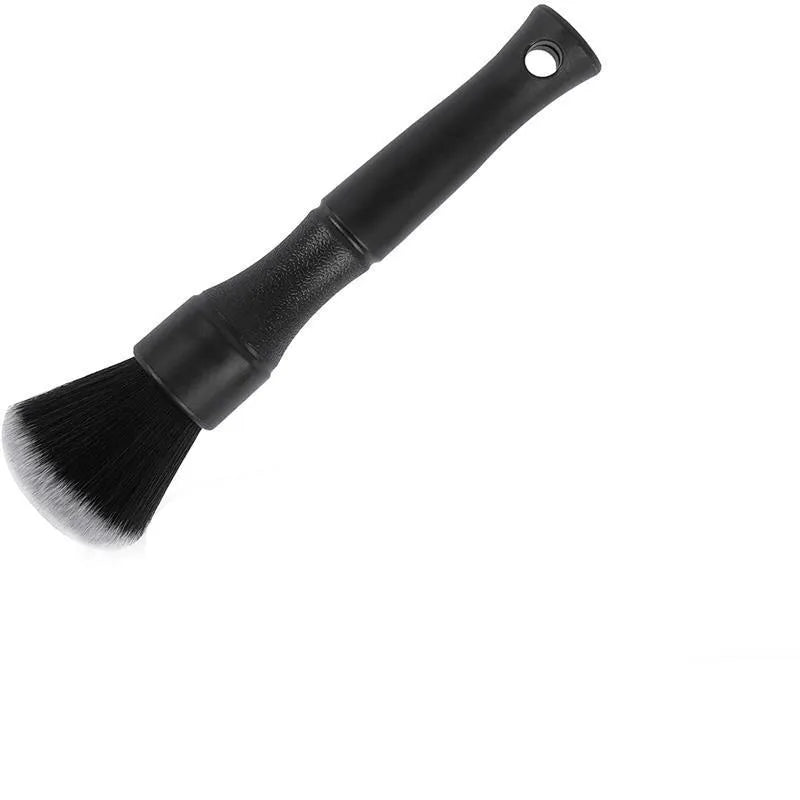 Black ultra-soft pig hair car detailing brush for interior cleaning on a car dashboard.