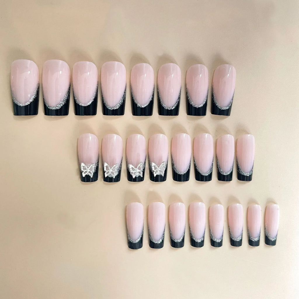 Black French-style false nails with glitter butterfly design on a hand.