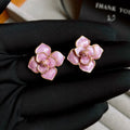 Close-up of a pair of purple and gold flower stud earrings with a textured oil-spot glaze finish.