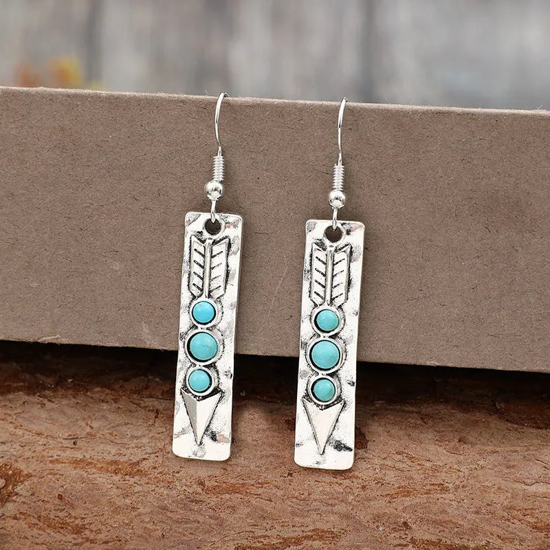 Silver geometric long strip earrings with inlaid turquoise details on a white background.