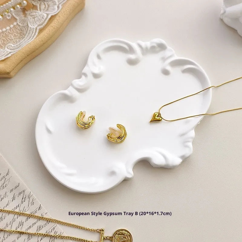European Baroque style gypsum jewellery display plate with rings and earrings on a dressing table