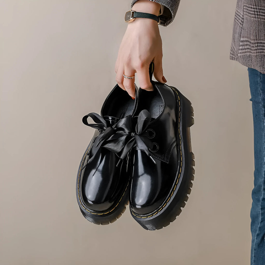Women's white and black thick soled leather shoes with cross strap and ribbon detail on a superfine fibre upper.