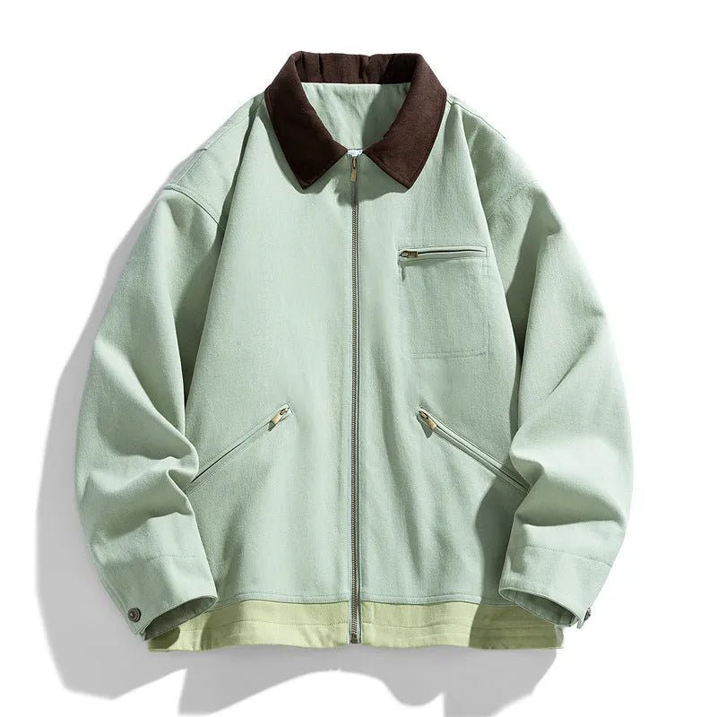 Man wearing a loose-fit mint green zip-up jacket with dark contrast lapels and side pockets.