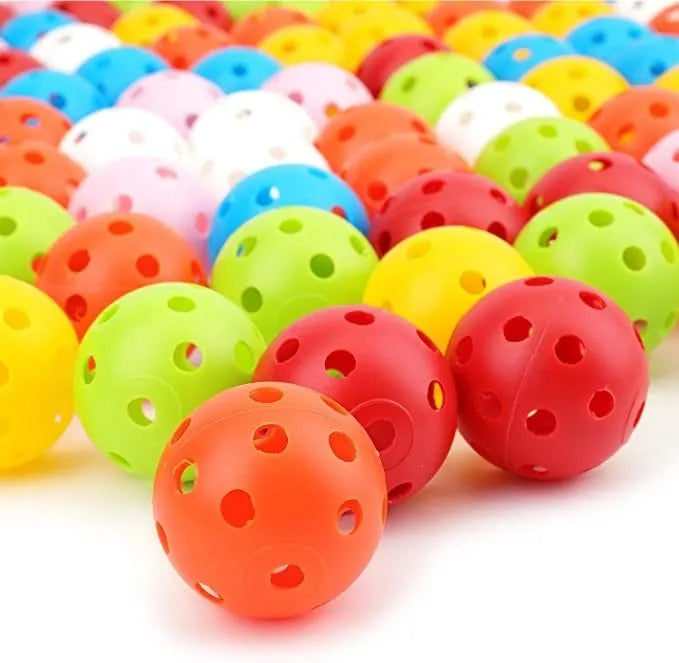 Six coloured 42mm golf practice balls in red, orange, blue, green, white and yellow arranged on putting surface