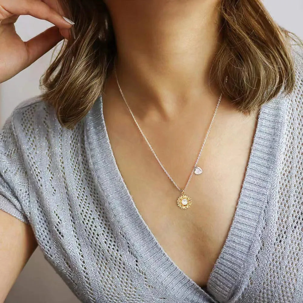 Close-up of a women's 925 silver necklace with a small daisy petal pendant on a cross chain, laid flat to show length.