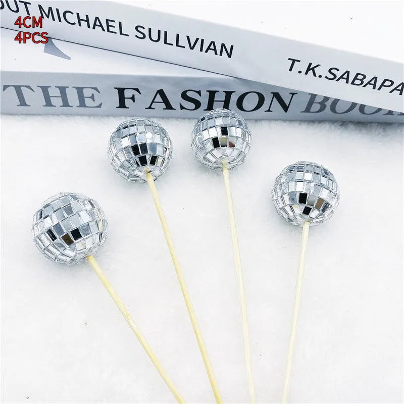 Glass disco ball cake decoration with wooden stick in various sizes on a birthday cake.