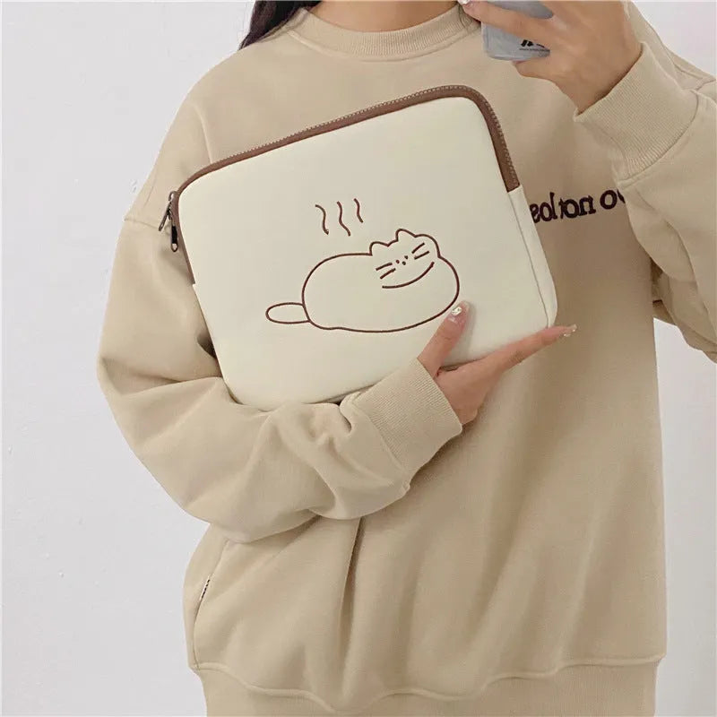 Embroidered fat cat design on a navy blue nylon laptop sleeve with a black zip