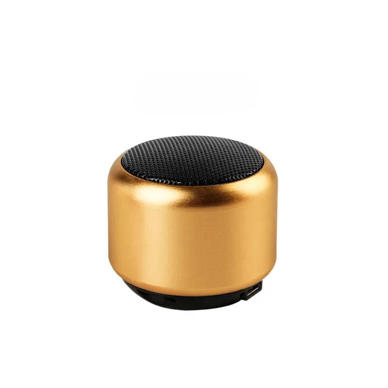 Small portable Bluetooth speaker in black, blue, gold, or pink colour on a table.