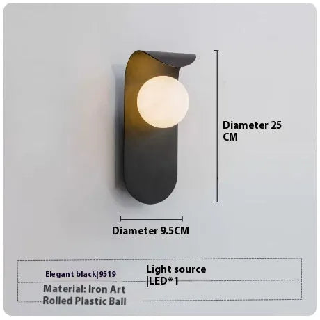 Modern minimalist black wall lamp with iron shade and LED light on a bedroom wall