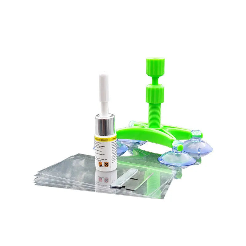 Windshield repair fluid kit with green resin, repair device, curing strips, and sleeved razor blade on a car windscreen
