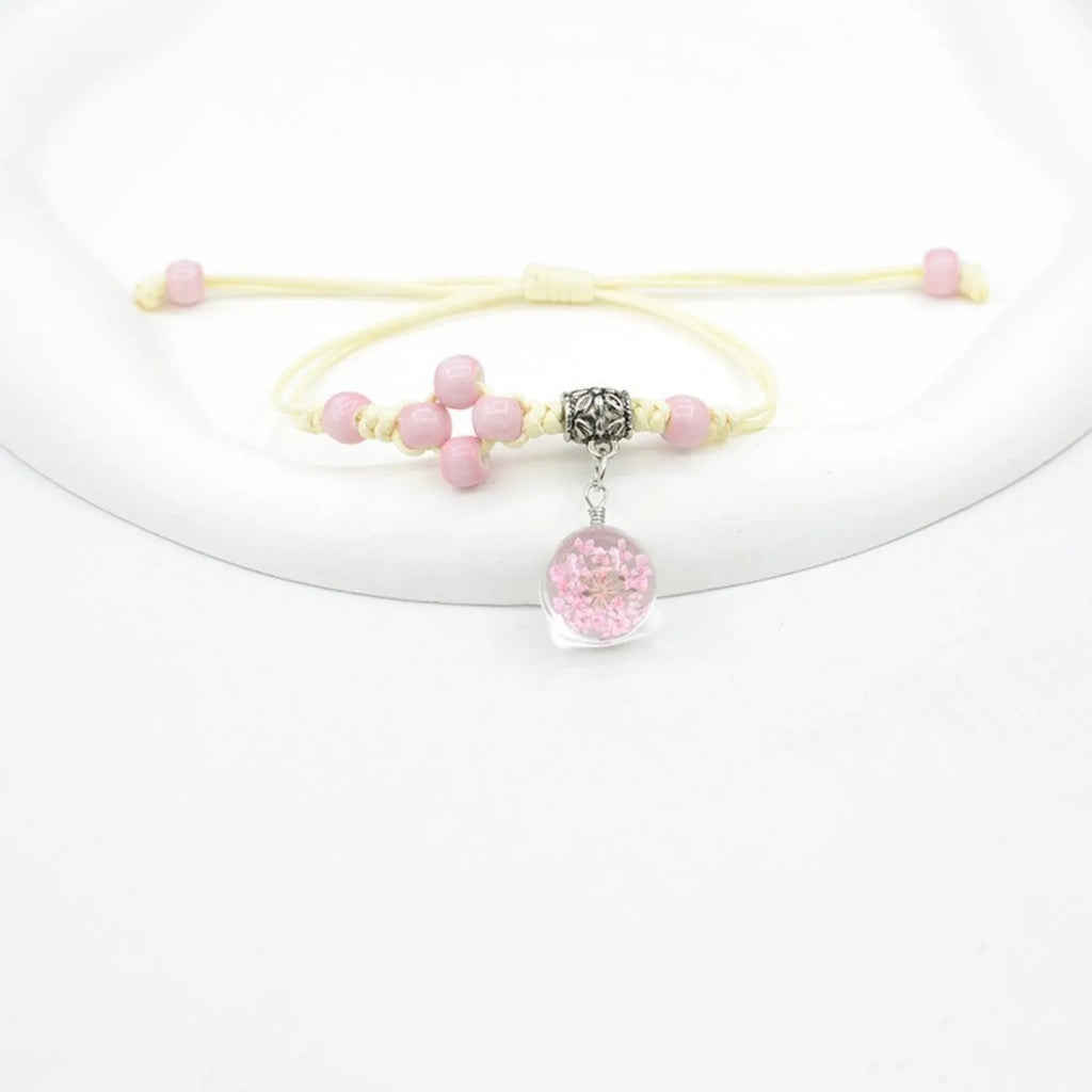 Close-up of a hand-woven glass bracelet with large beads containing real dried flowers and a lace design.