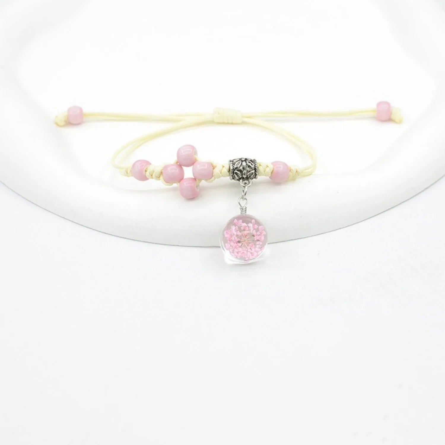 Close-up of a hand-woven glass bracelet with large beads containing real dried flowers and a lace design.