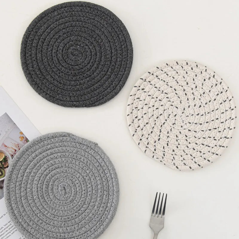 Set of three round grey cotton cord coasters, each 18 cm in diameter, on a wooden table.