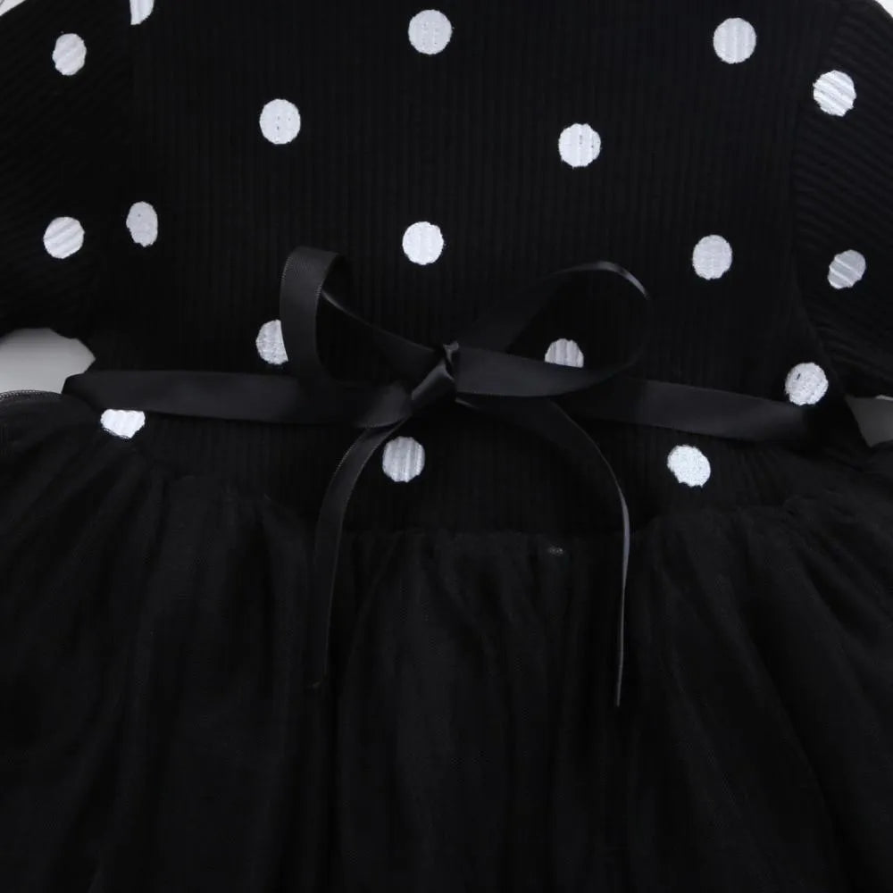 Baby girl wearing a long sleeve white lace tutu dress for a birthday or christening.