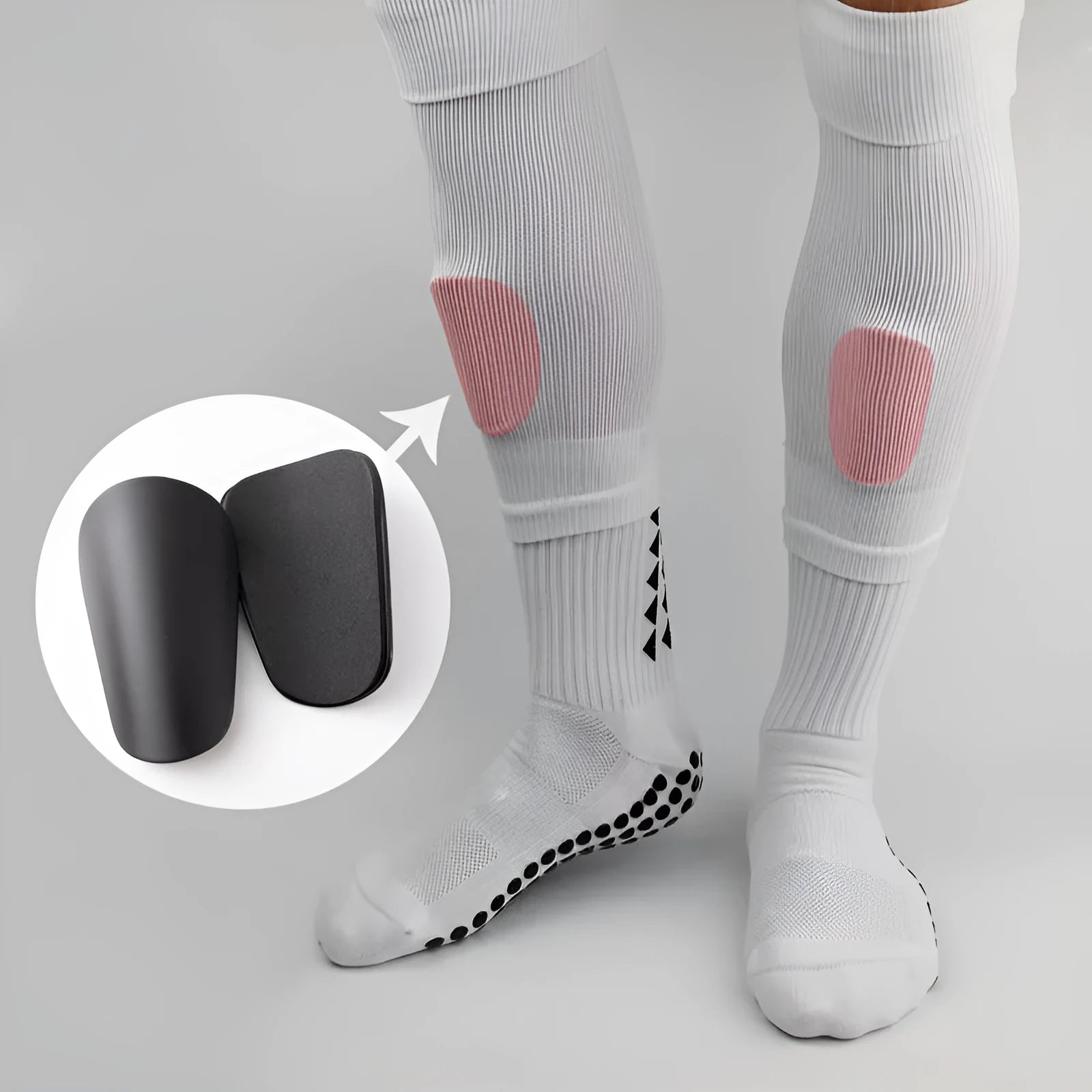 Two pairs of PU mini shin guards in black, white, red, and dream blue colours on a sports field.