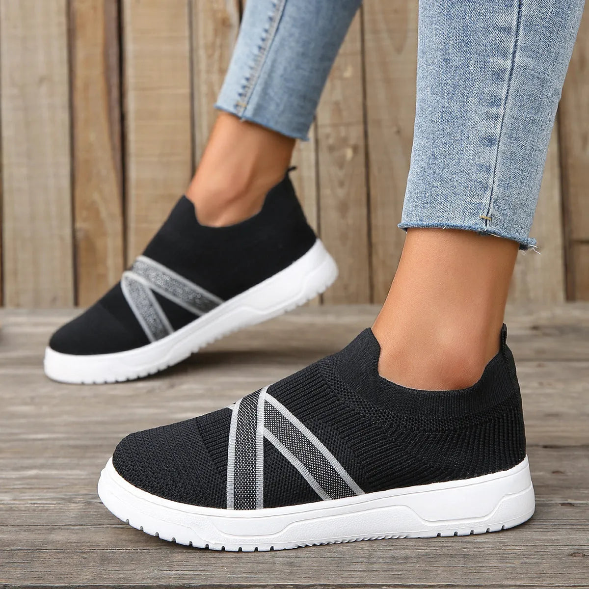 Black women's casual trainers with flyknit mesh upper, flat rubber sole, round toe, and a tassel detail.