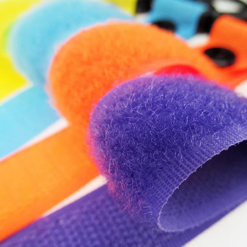 A selection of luggage Velcro hooks in various colours including red, blue, green, and yellow on a white background